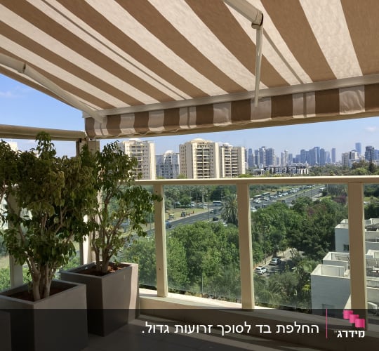 סוכך זרועות מתקפל עם בד פסים חום-לבן במרפסת שמש